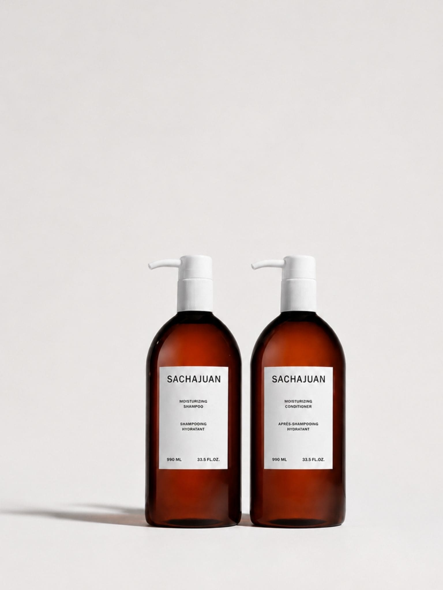 Two amber glass pump bottles with white labels reading SACHAJUAN, photographed on a clean light gray studio background.